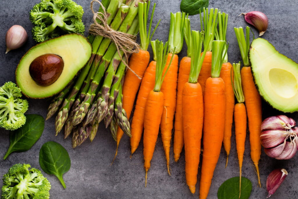Bunch of fresh asparagus and vegetables on wooden table.